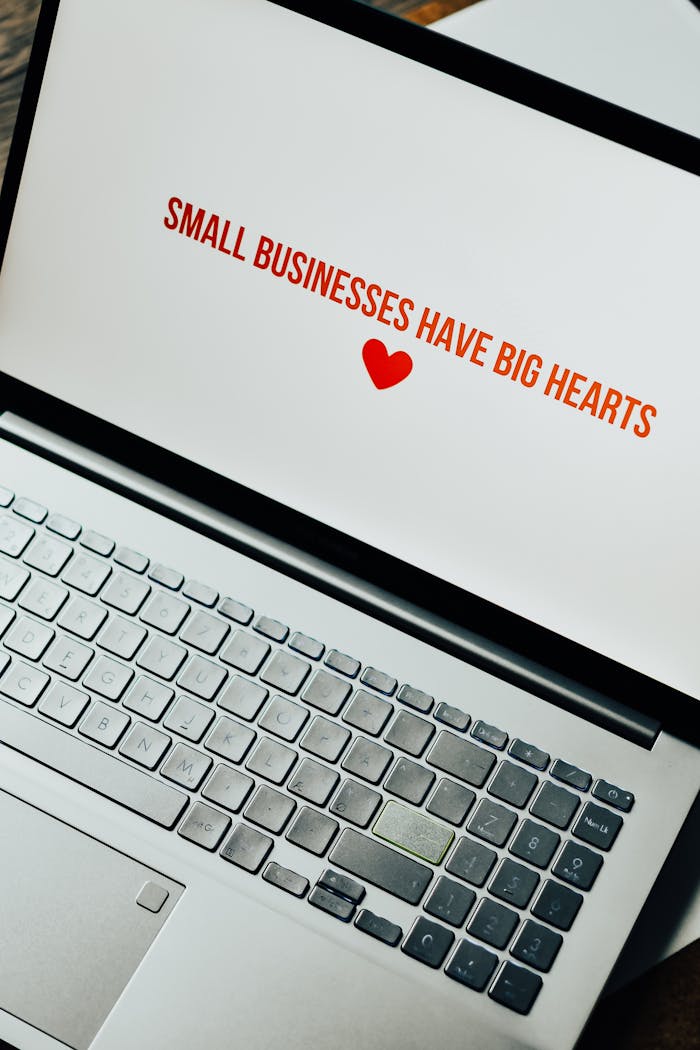 Close-up of laptop displaying 'Small Businesses Have Big Hearts' message with a heart icon.